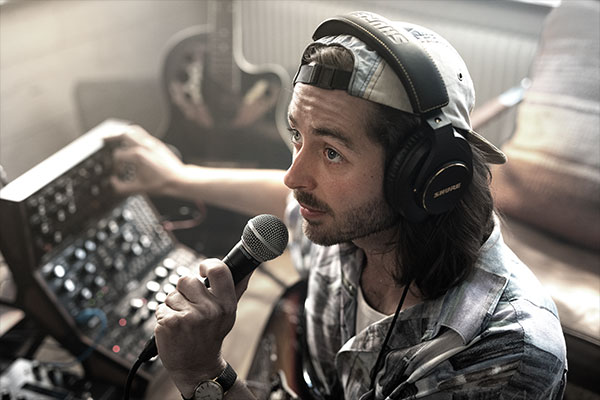 Hombre con gorra grabando voz con micrófono Shure SM58